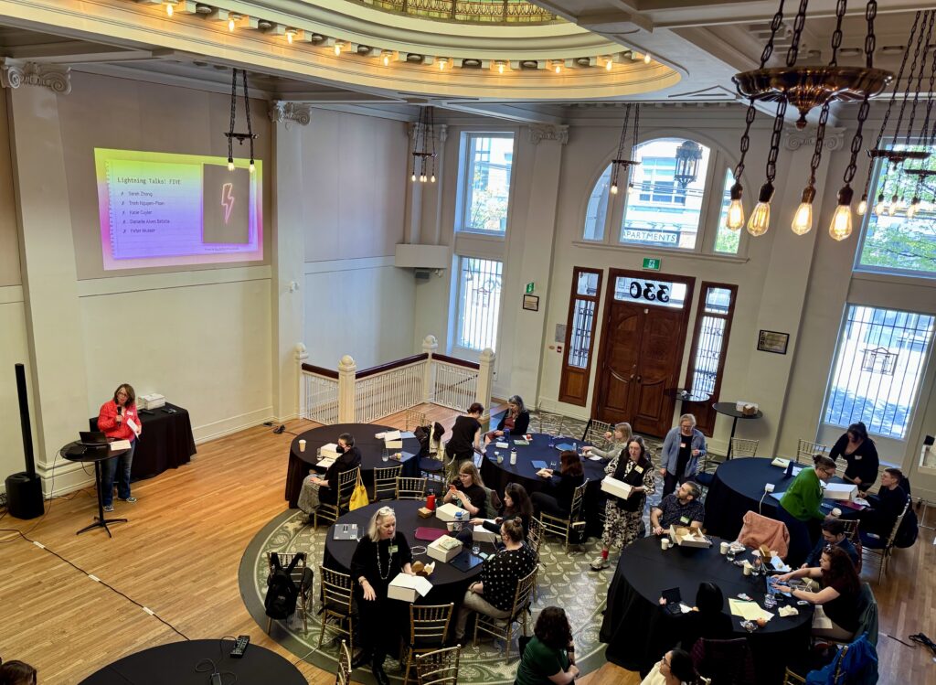 image of a group of people sitting at round tables listening to a presentation.